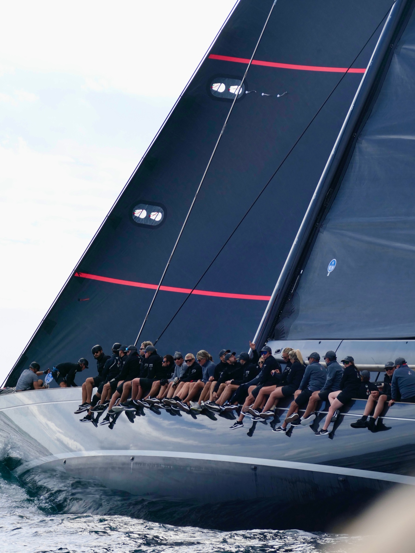 Professional superyacht crew at the rail of a luxury yacht at golden hour